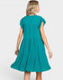 A woman wearing a teal green tiered dress, shown from the back against a light gray studio background.