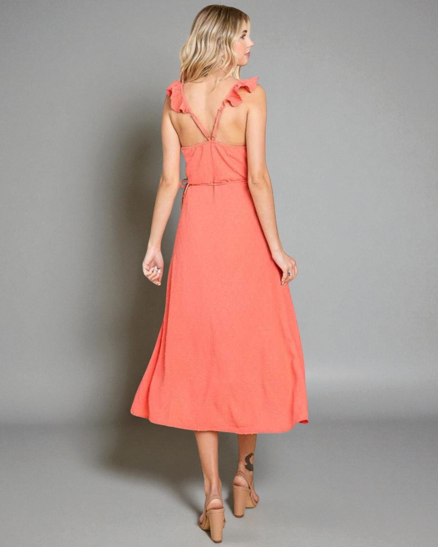 Woman wearing a coral dress against a gray background