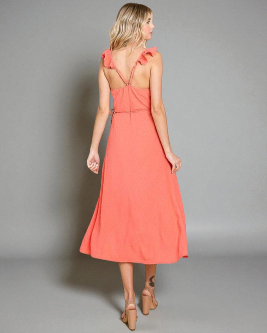 Woman wearing a coral dress against a gray background