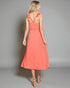 Woman wearing a coral dress against a gray background
