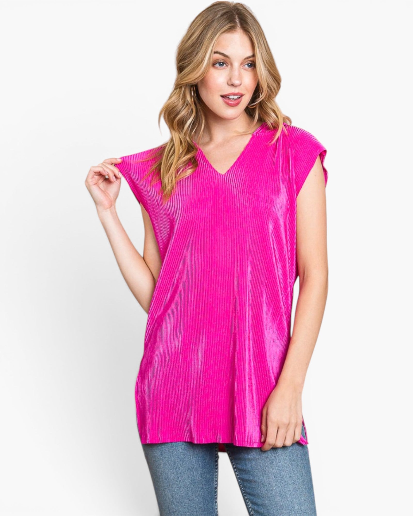 A woman modeling a bright pink short-sleeve V-neck top with a textured, ribbed fabric, paired with blue jeans against a plain white studio background.