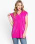 A woman modeling a bright pink short-sleeve V-neck top with a textured, ribbed fabric, paired with blue jeans against a plain white studio background.
