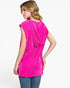 A woman wearing a bright hot pink sleeveless draped tunic top with blue jeans, shown from a three-quarters back view against a plain white studio background.