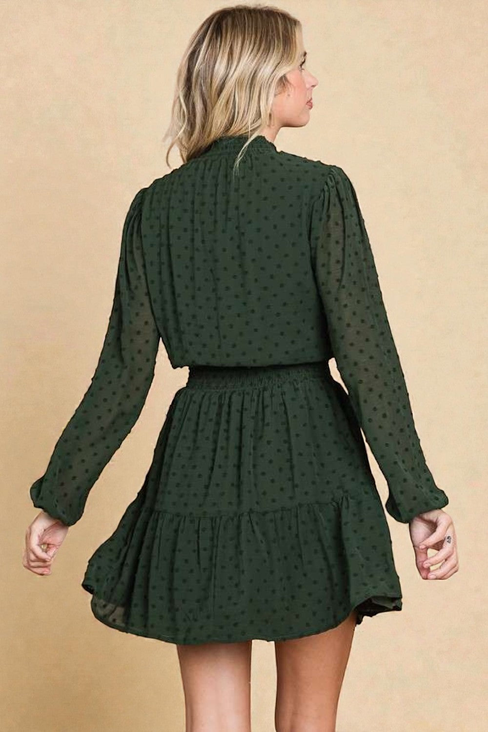 Woman wearing a green polka dot dress against a beige background