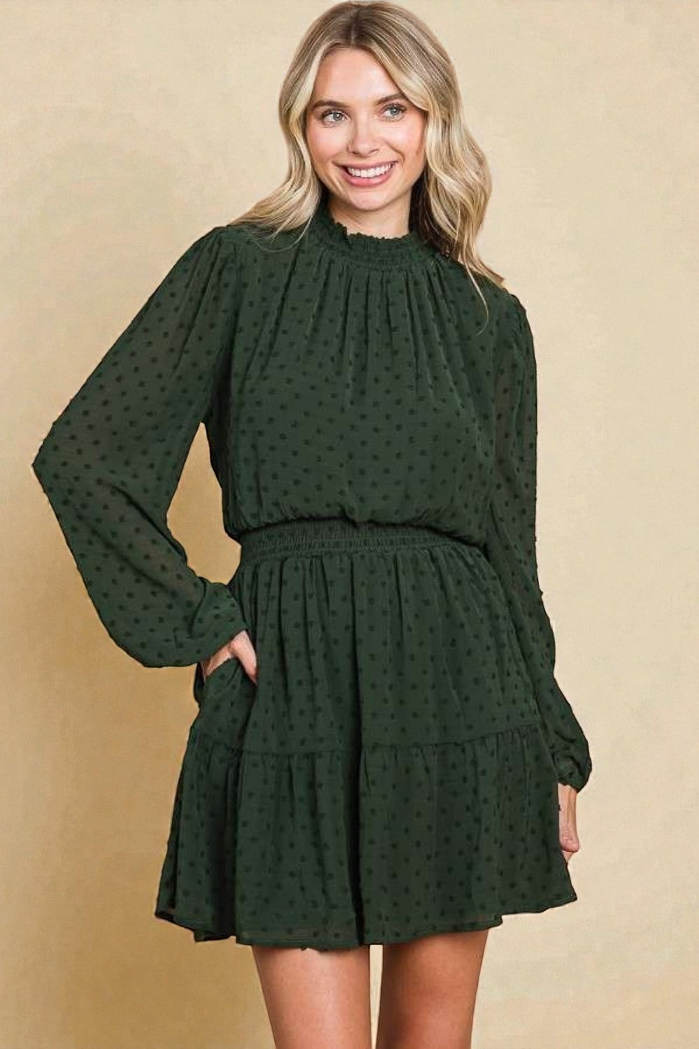 Woman wearing a green polka dot dress against a beige background