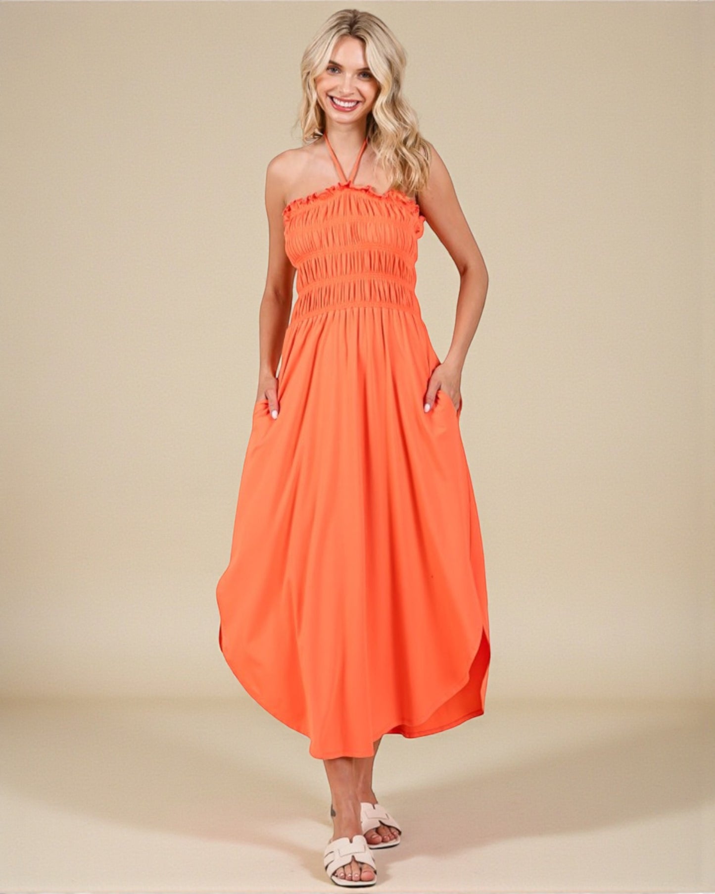 Woman wearing an orange halter neck dress on a beige background