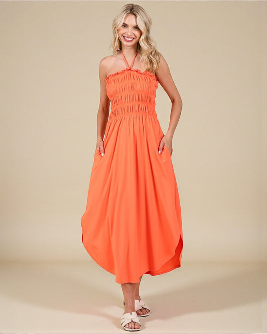 Woman wearing an orange halter neck dress on a beige background