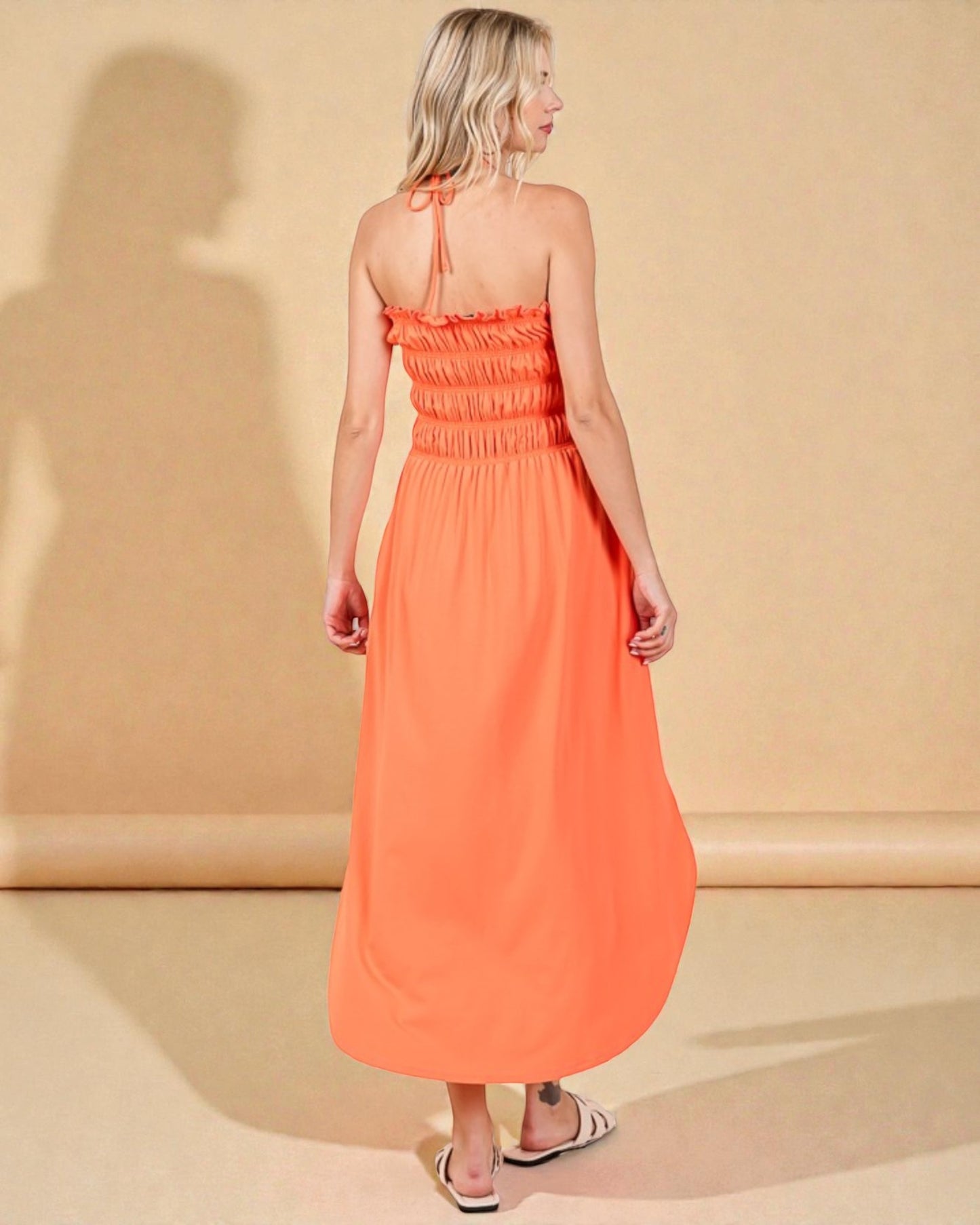 Woman wearing an orange dress against a beige background