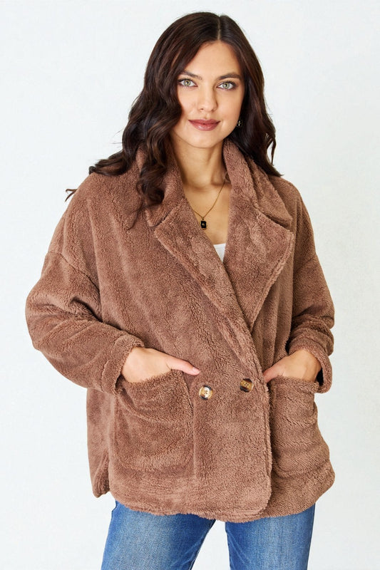 Woman wearing a brown teddy coat on a white background