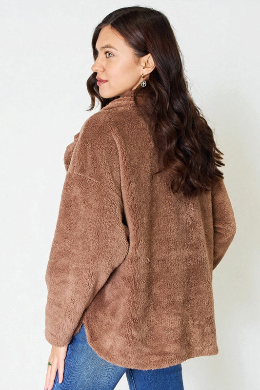 Woman wearing a brown fleece jacket against a white background