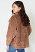 Woman wearing a brown fleece jacket against a white background