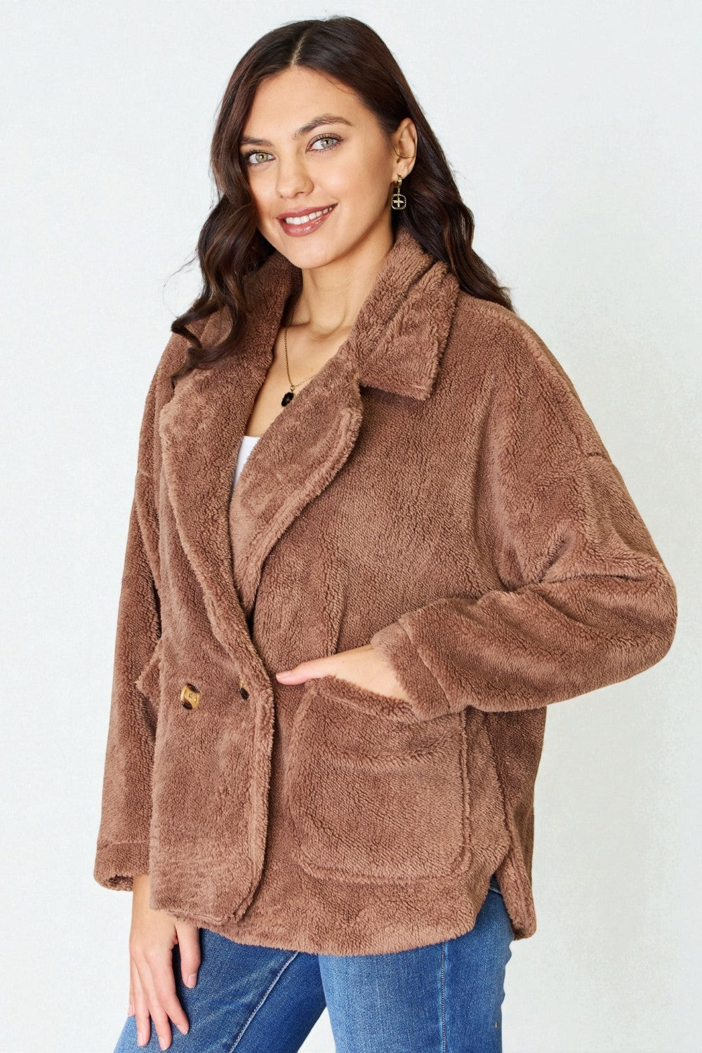 Woman wearing a brown teddy coat against a white background