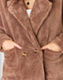 Brown fluffy coat with button details on a neutral background