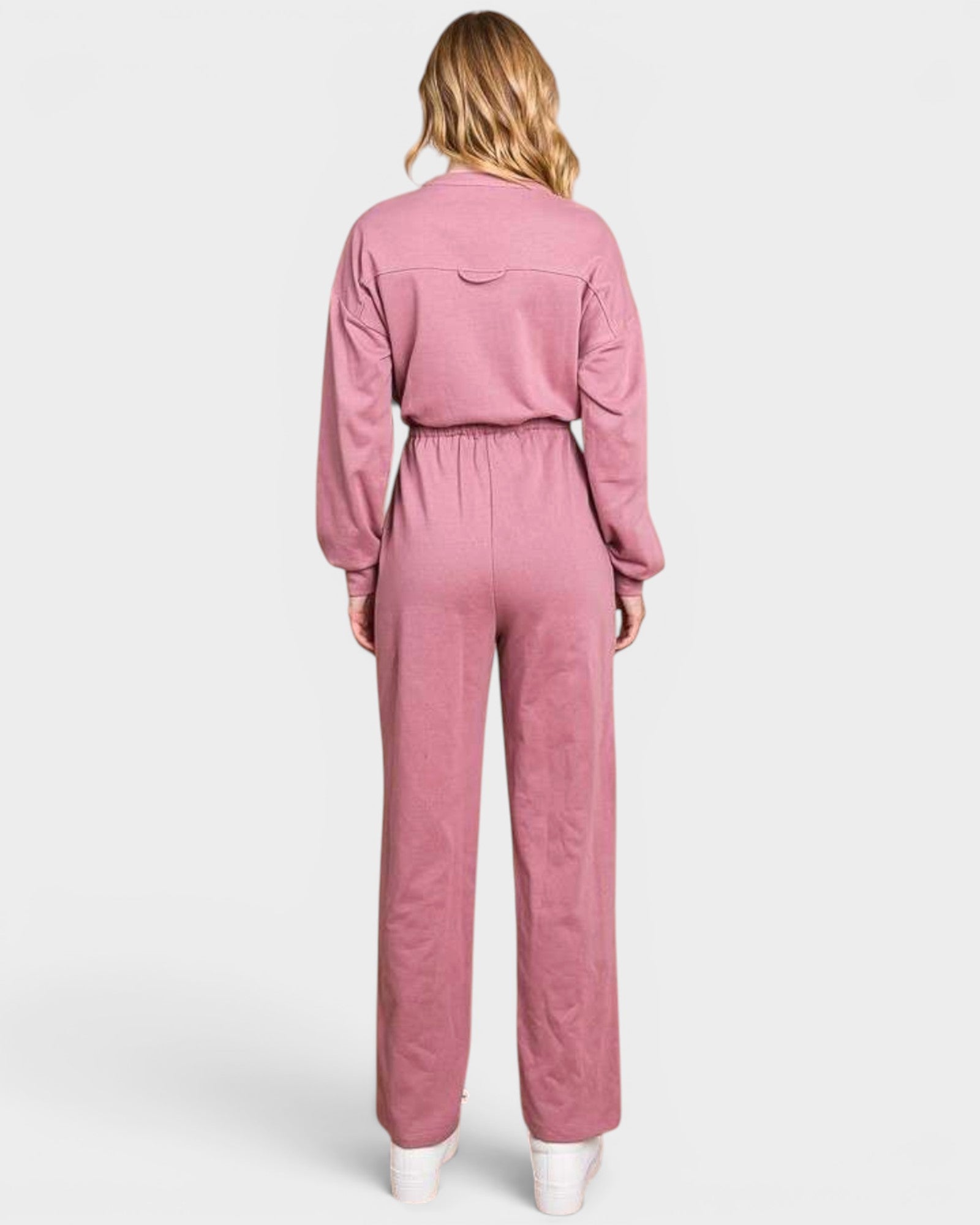 Person wearing a pink jumpsuit on a white background