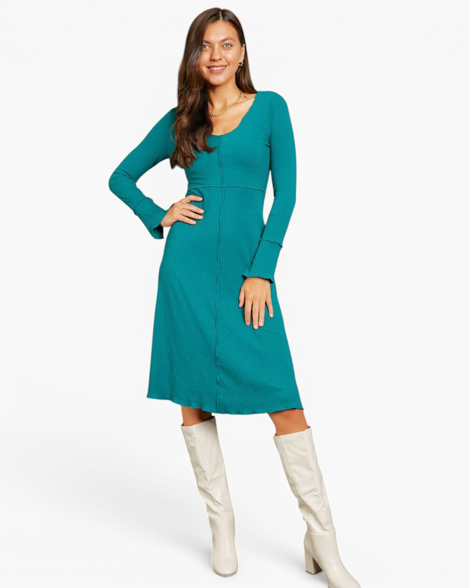 A woman modeling a teal long-sleeve midi dress with a V-neck and front button detail, paired with off-white knee-high boots, against a plain white studio background.