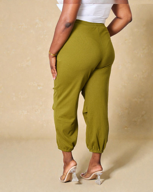 Person wearing green pants and white top on a beige background