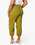 A model shown from the back wearing olive green jogger pants with elastic cuffs, paired with a white top and clear high-heeled sandals, against a plain white background.
