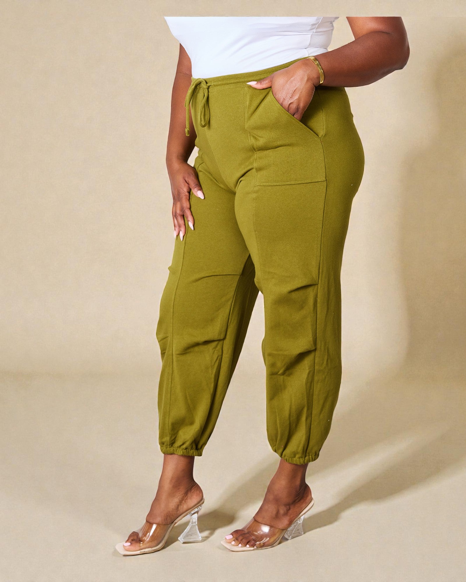 Person wearing green cargo pants on a beige background
