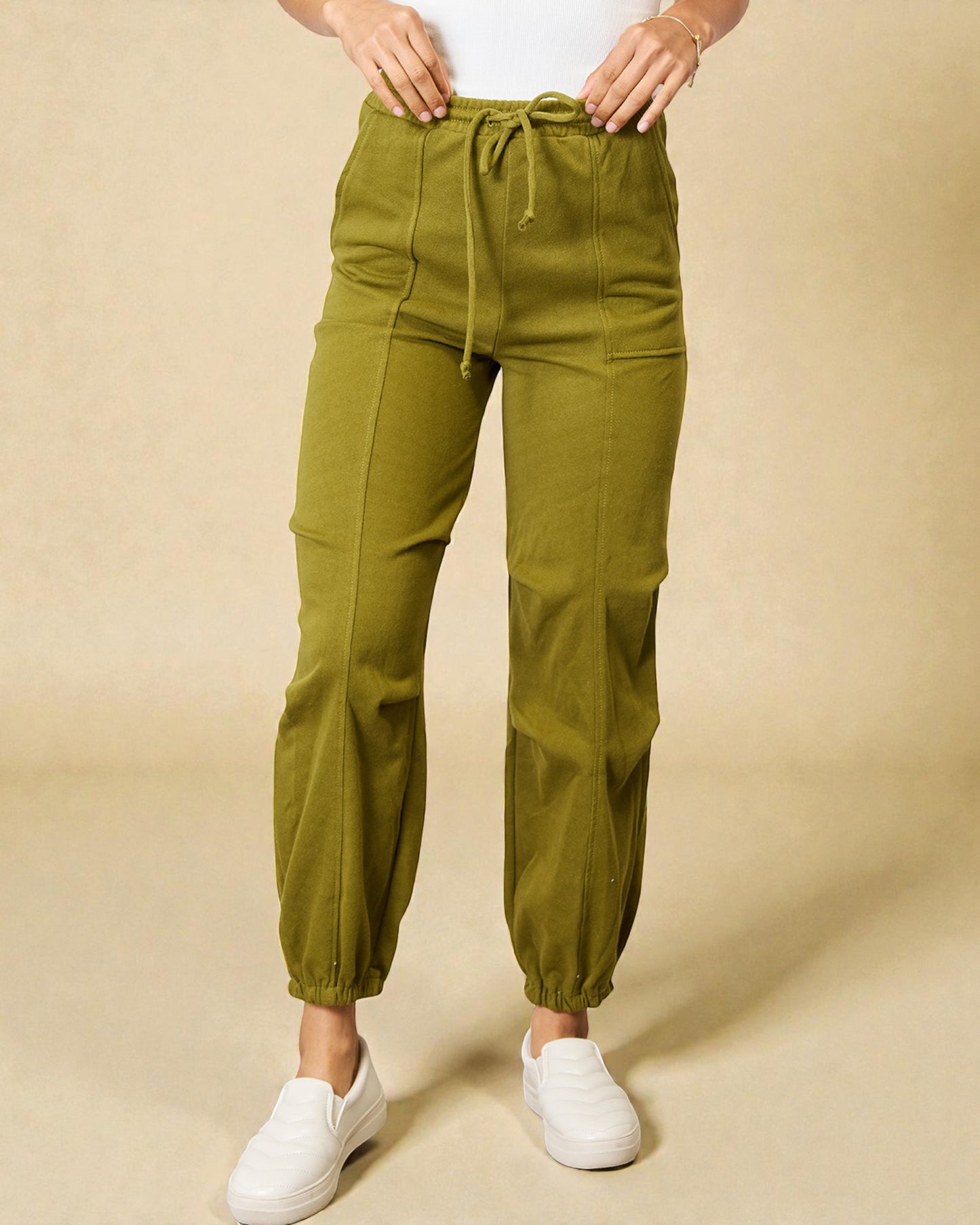 Green cargo pants worn by a person on a beige background