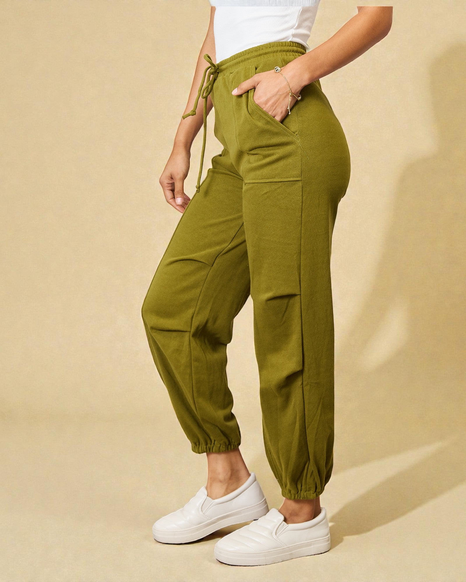 Person wearing green cargo pants and white sneakers on a beige background