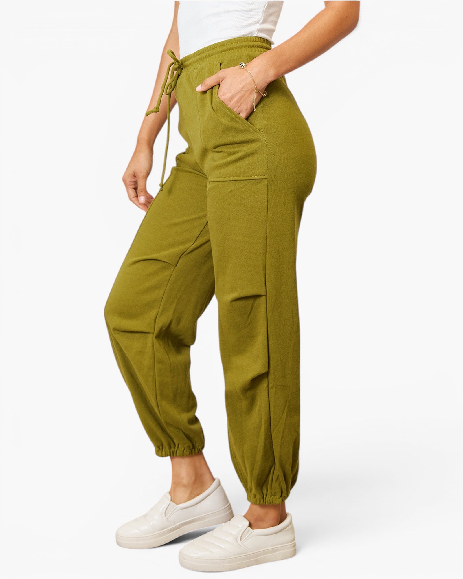 A person wearing olive green drawstring jogger pants with side pockets and elastic cuffs, paired with white sneakers, shown against a plain light background.