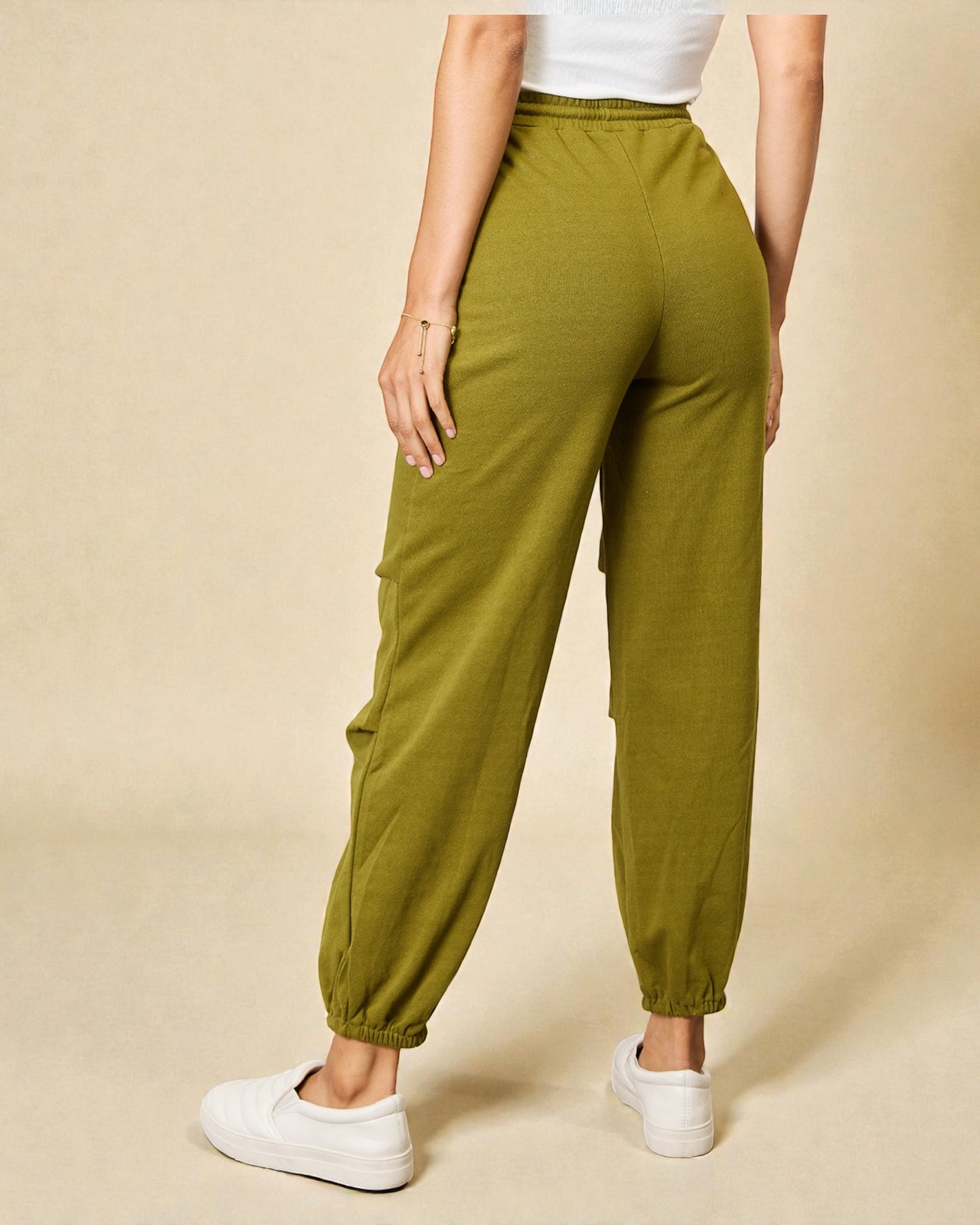 Person wearing green jogger pants on a beige background
