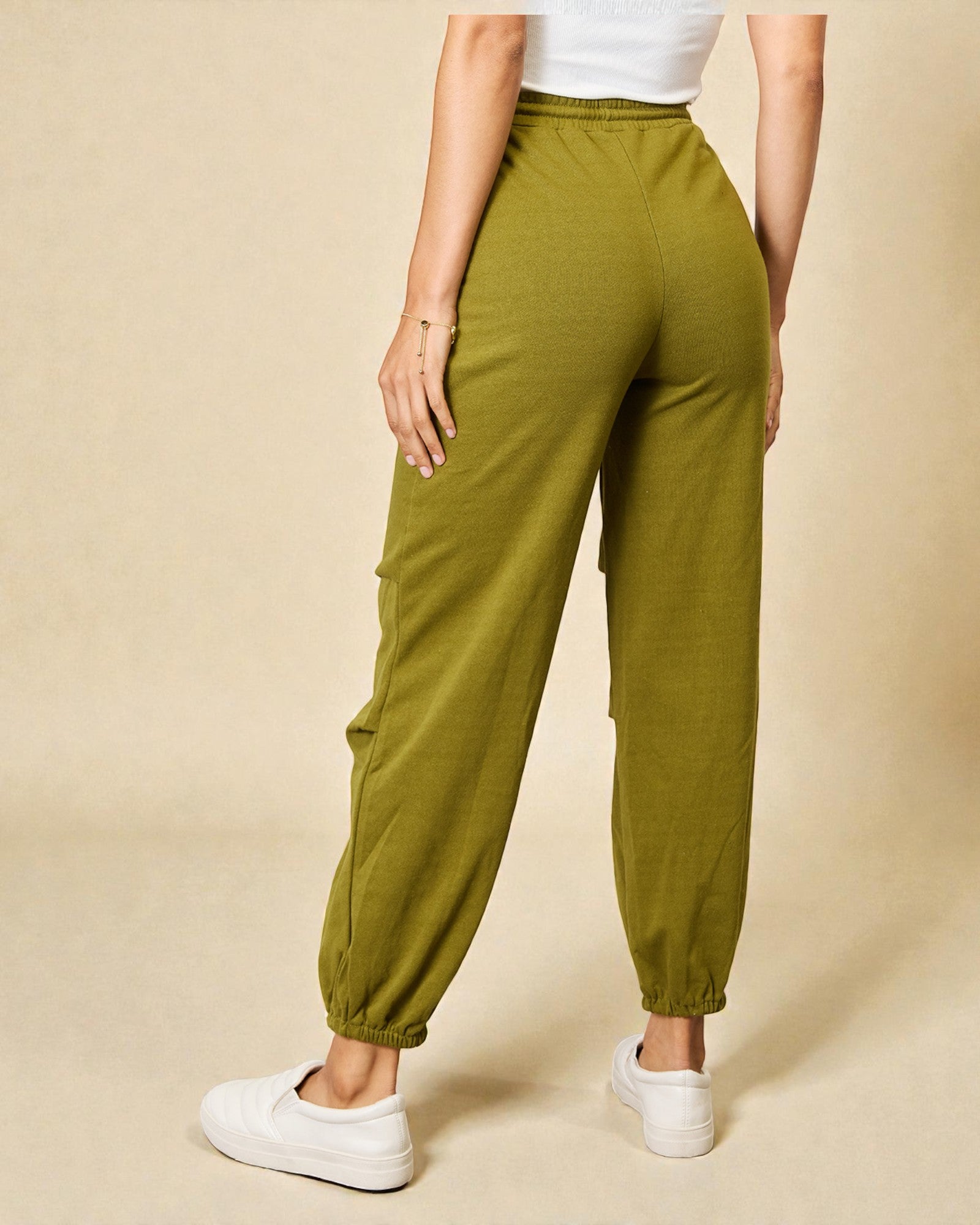 Person wearing green jogger pants on a beige background