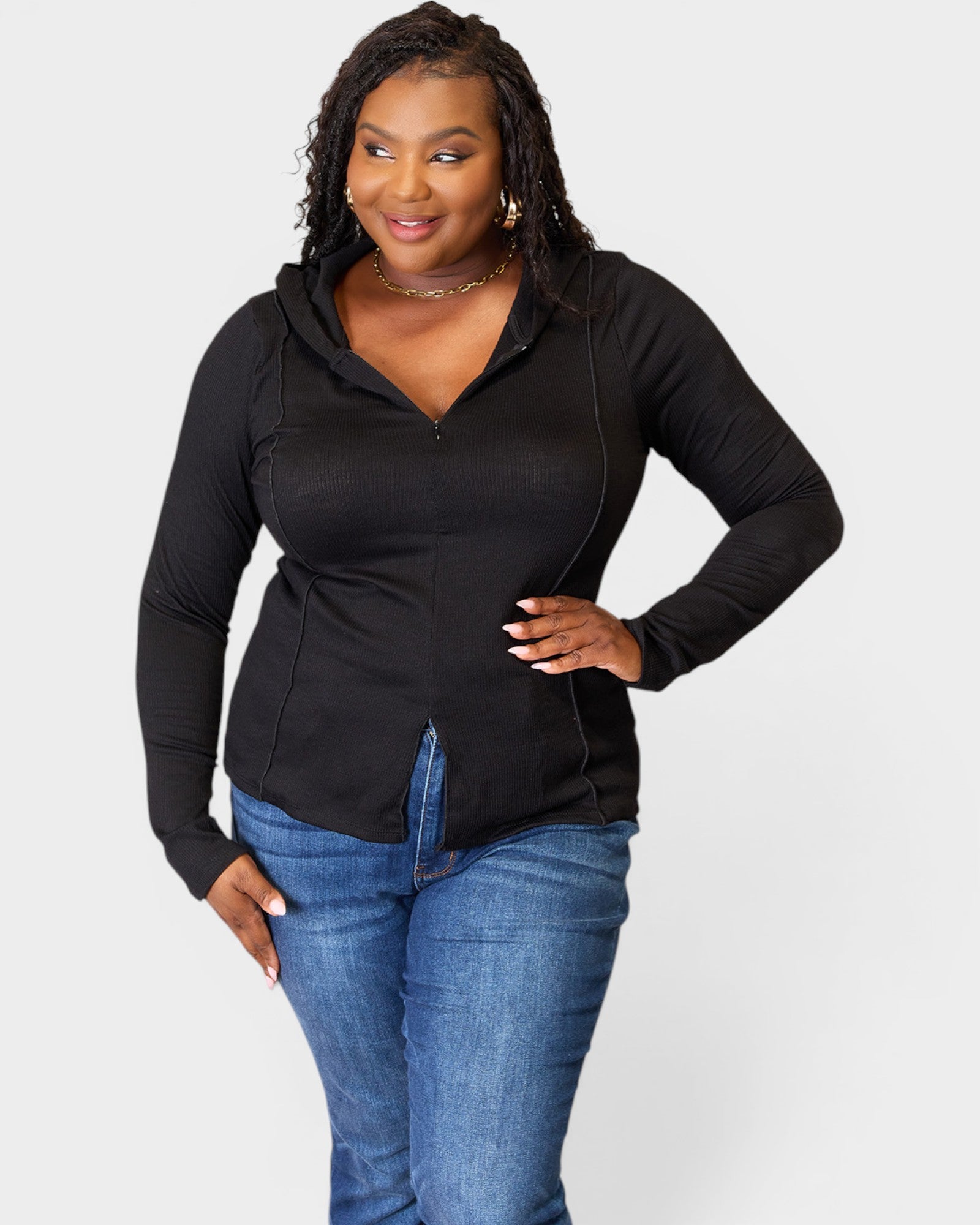 Woman wearing a black long-sleeve top and blue jeans on a white background