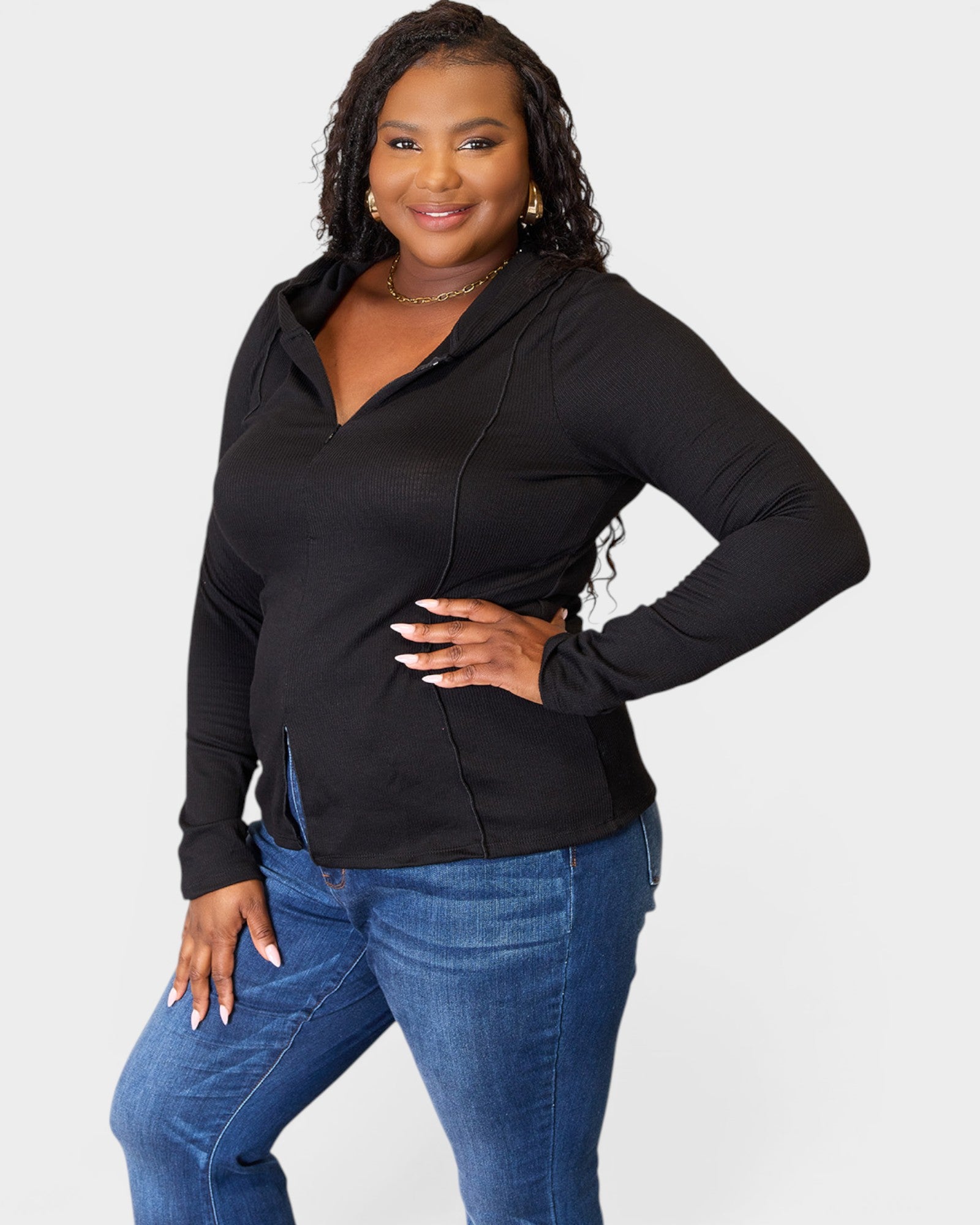 Woman wearing a black hoodie and blue jeans on a white background