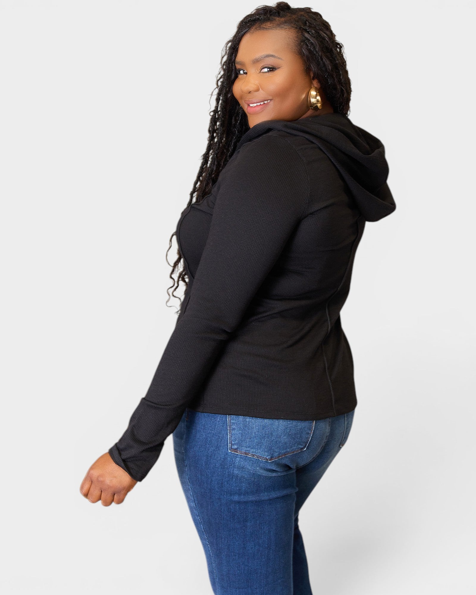 Woman wearing a black hoodie and blue jeans on a white background