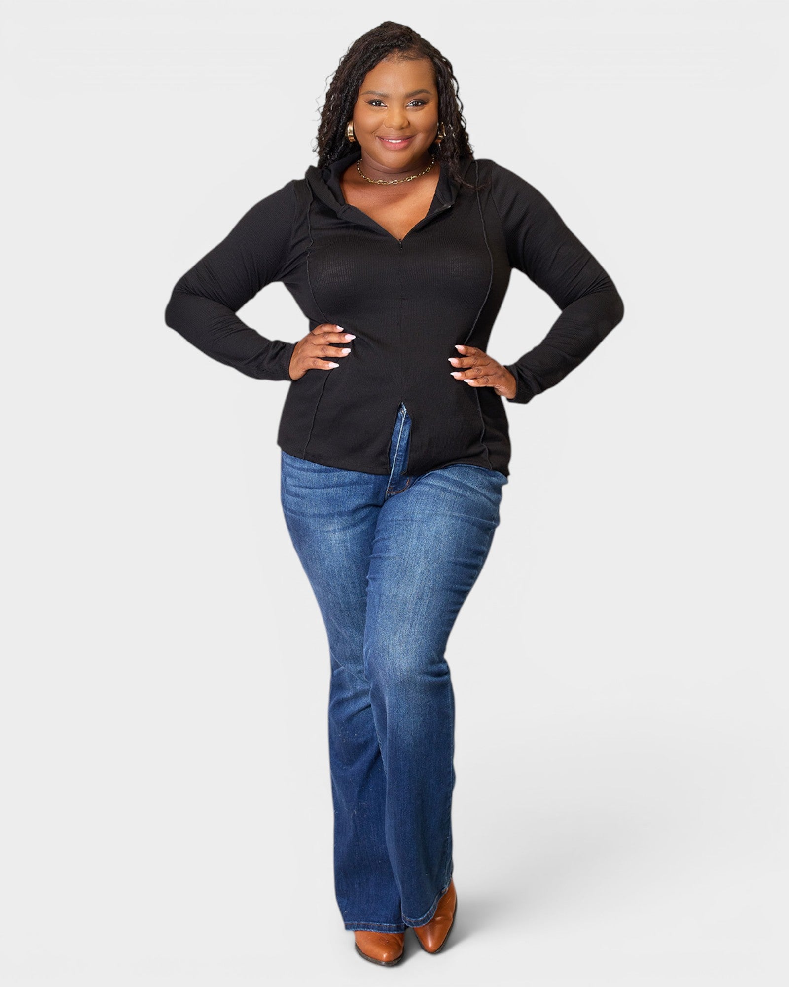 Woman wearing a black long-sleeve top and blue jeans on a white background