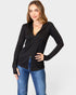 Woman wearing a black long-sleeve top and blue jeans on a white background