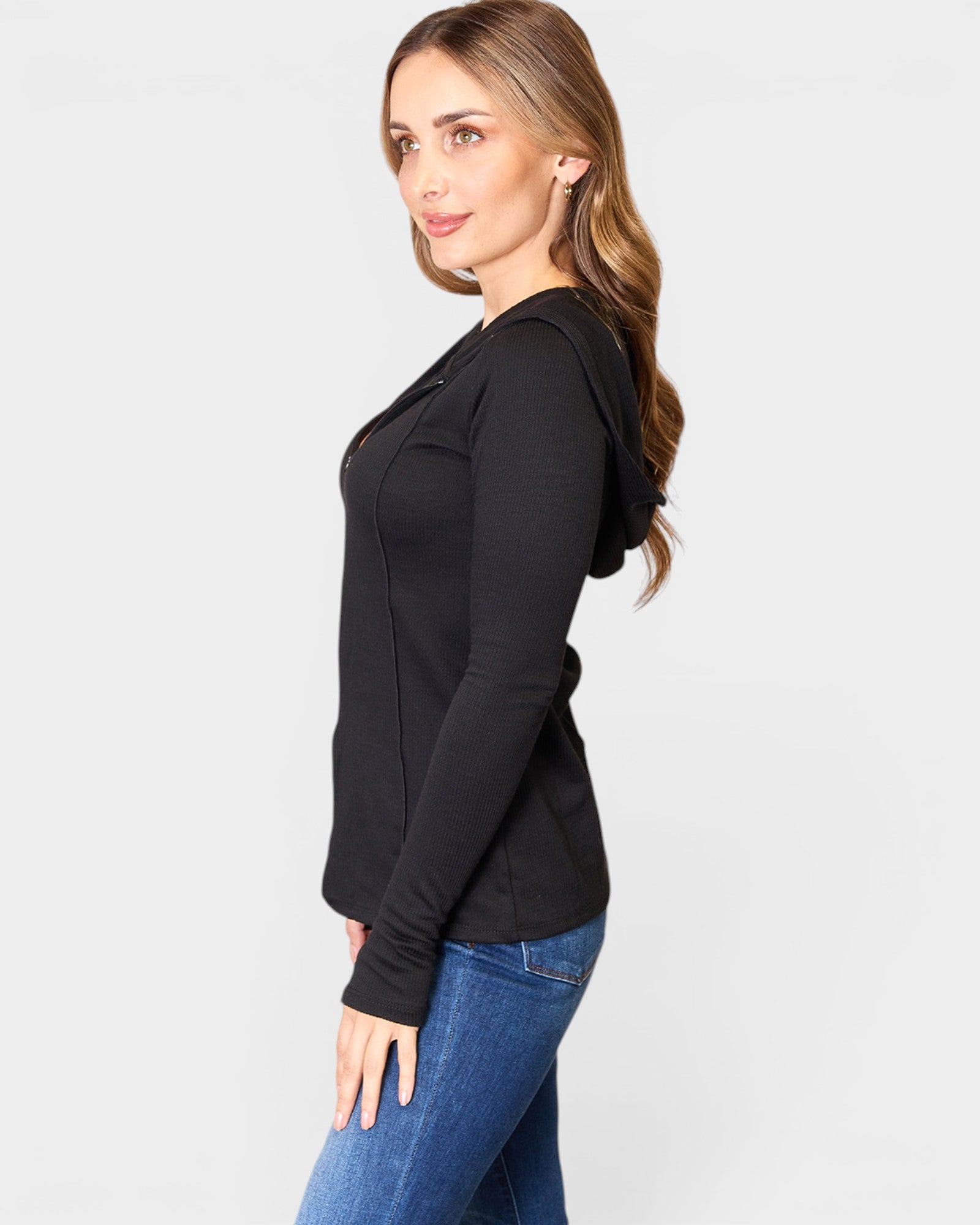 Woman wearing a black long-sleeve top and blue jeans on a white background