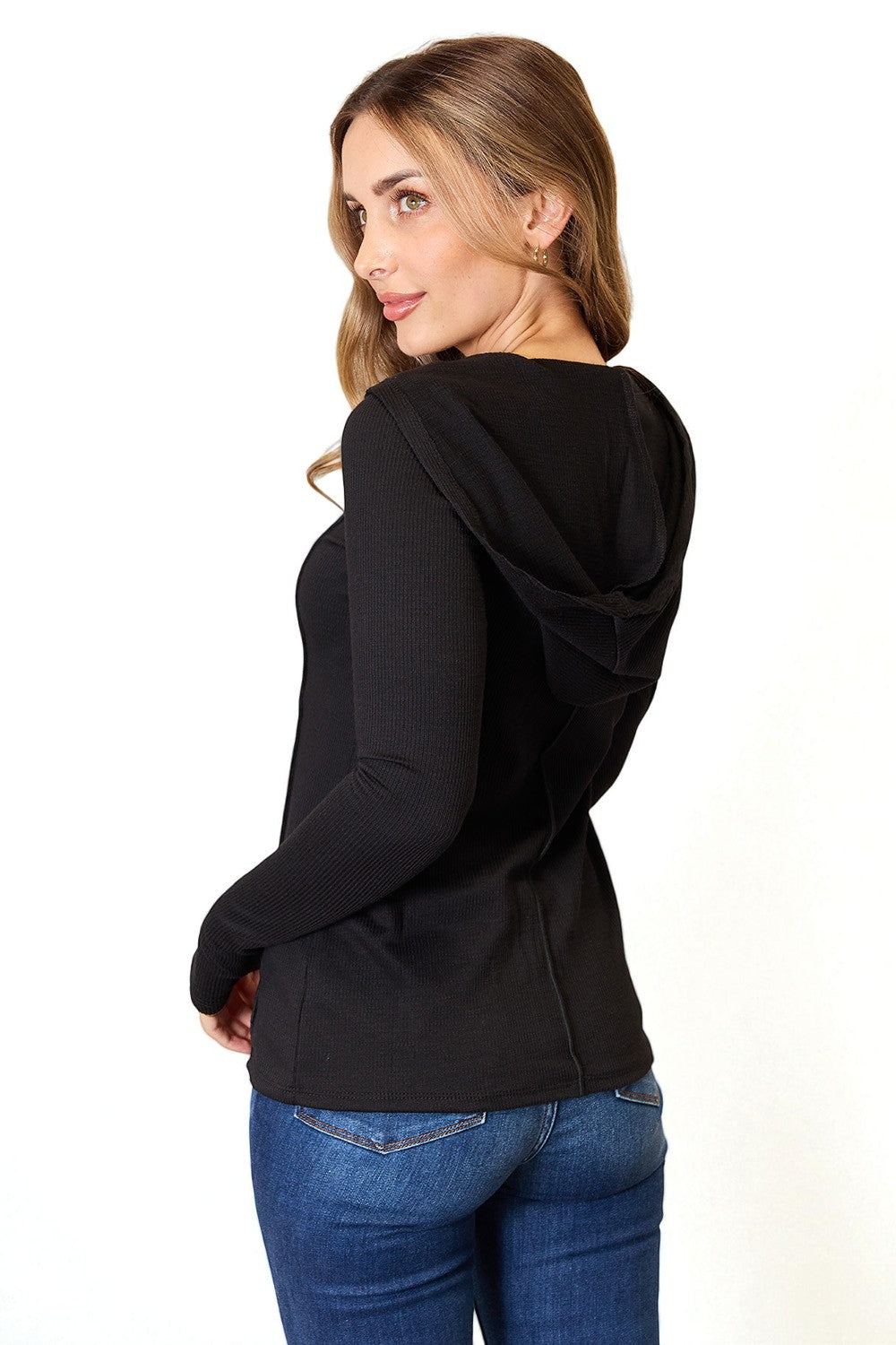 Woman wearing a black hoodie and blue jeans on a white background