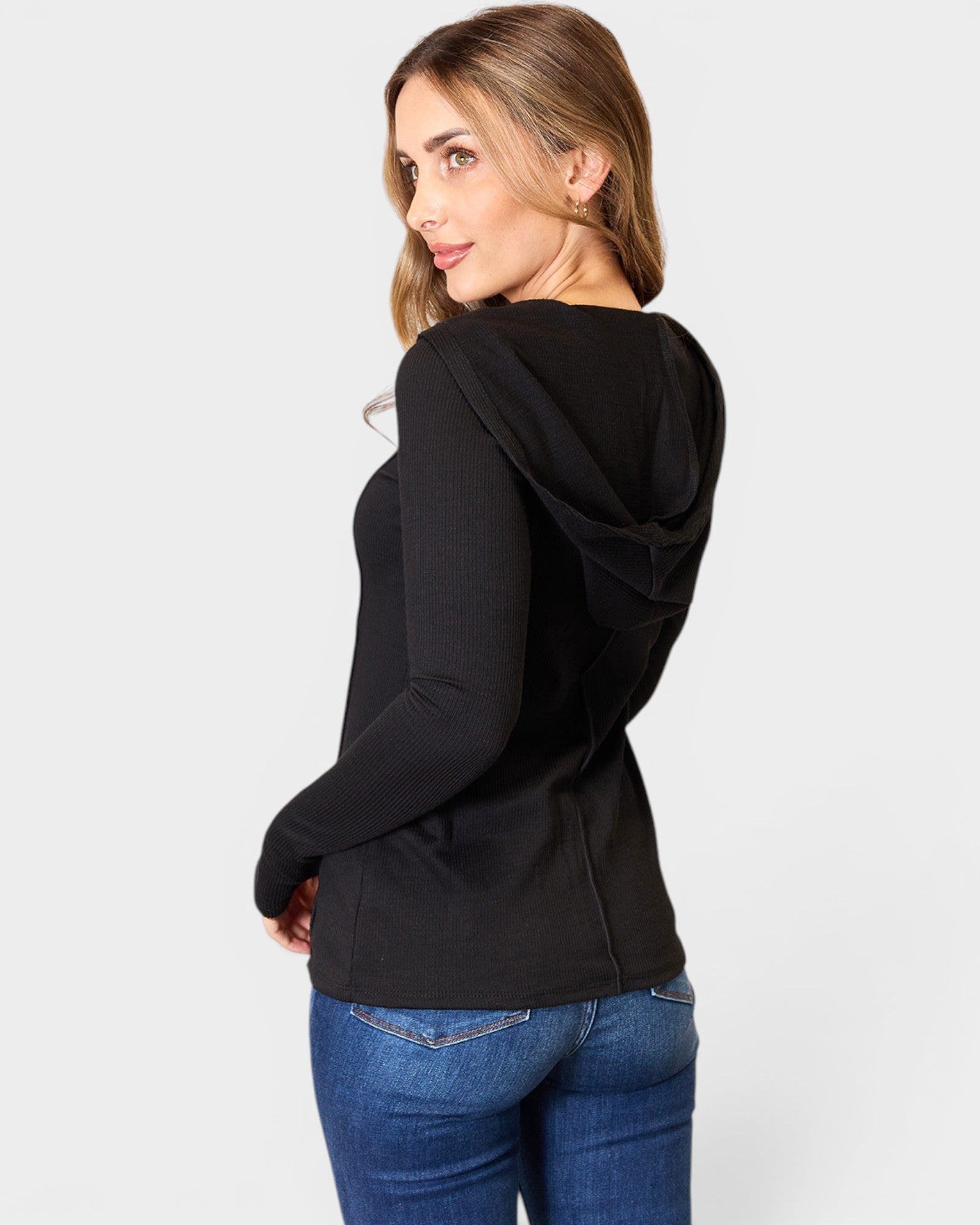 Woman wearing a black hoodie and blue jeans on a white background