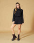 Woman wearing a black outfit with burgundy boots on a beige background