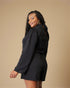 Woman wearing a black long-sleeve romper against a beige background