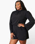 A woman modeling a black long-sleeve romper with a gathered mock neck and flared sleeves, photographed against a clean white studio background.