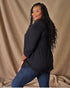 Woman wearing a black top and blue jeans against a beige background