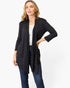 A woman modeling a black long-sleeve open-front cardigan over a white top and blue jeans, photographed against a clean white studio background.