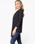 A woman modeling a black three-quarter sleeve open-front cardigan or tunic top with a split neckline, paired with dark blue jeans, against a plain white studio background.