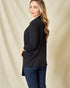 Woman wearing a black long-sleeve top and blue jeans against a beige background