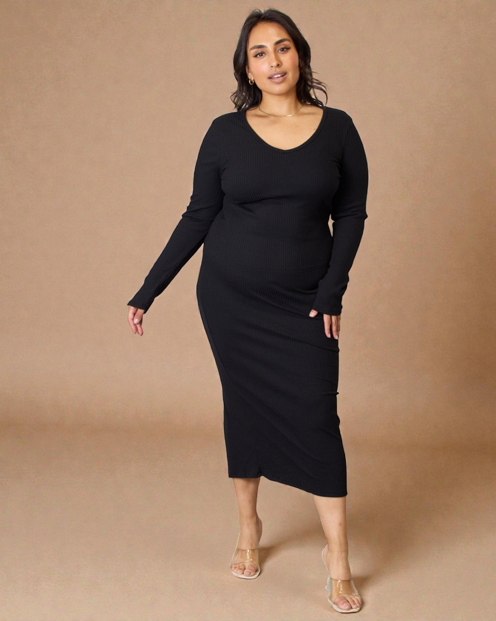 Woman wearing a black long-sleeve dress against a beige background