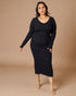 Woman wearing a black long-sleeve dress against a beige background