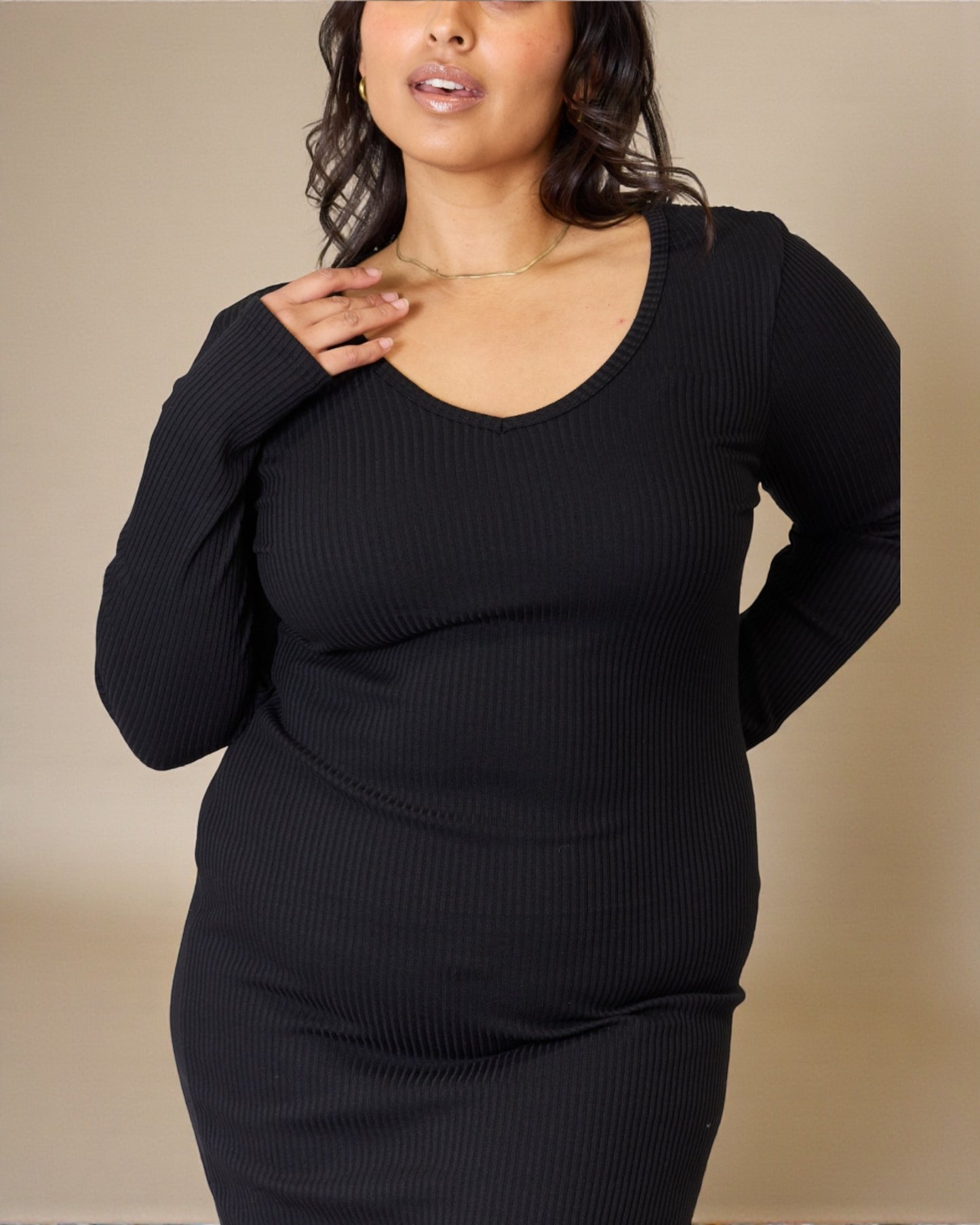 Woman wearing a black ribbed sweater against a beige background