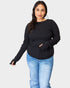 Woman wearing a black long-sleeve top and blue jeans on a white background