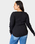 Person wearing a black long-sleeve top and blue jeans on a white background