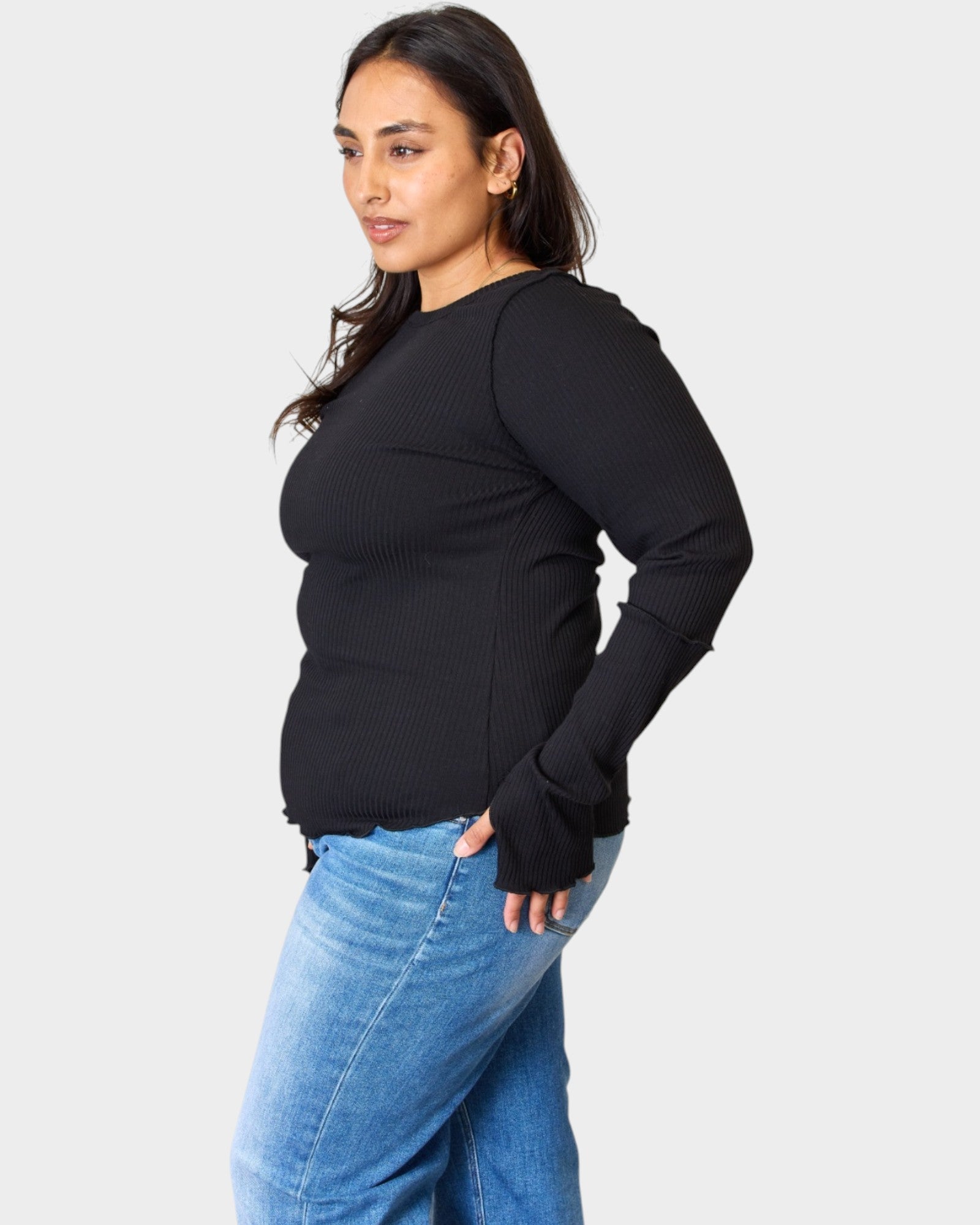 Woman wearing a black sweater and blue jeans on a white background