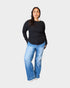 Woman wearing a black long-sleeve top and blue jeans on a white background