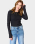 Woman wearing a black long-sleeve top and blue jeans on a white background
